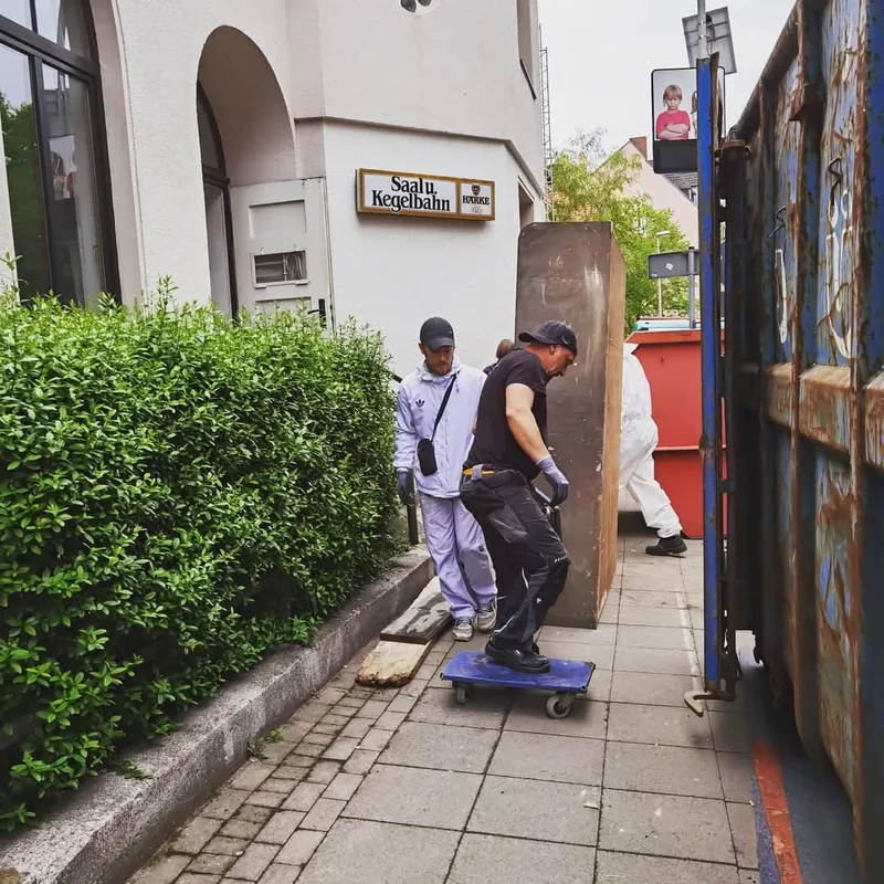 Zwei Mitarbeiter transportieren Möbel mit einem Rollbrett