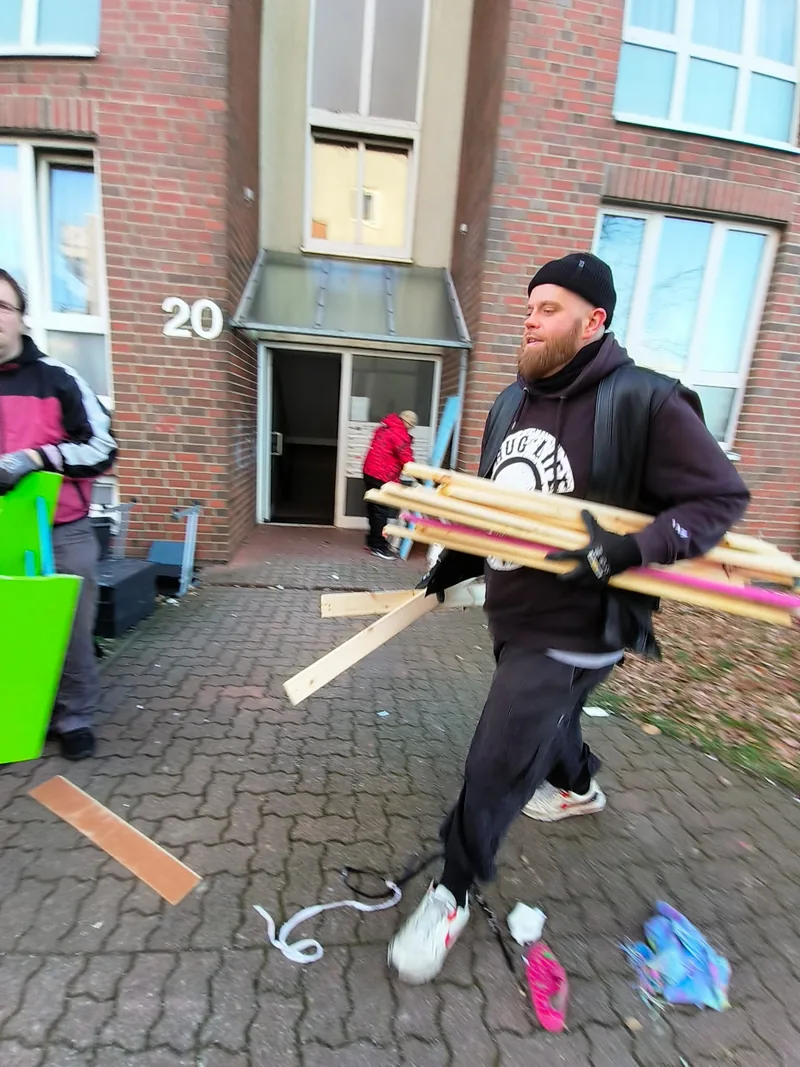 Mitarbeiter trägt Bretter aus einem Hauseingang