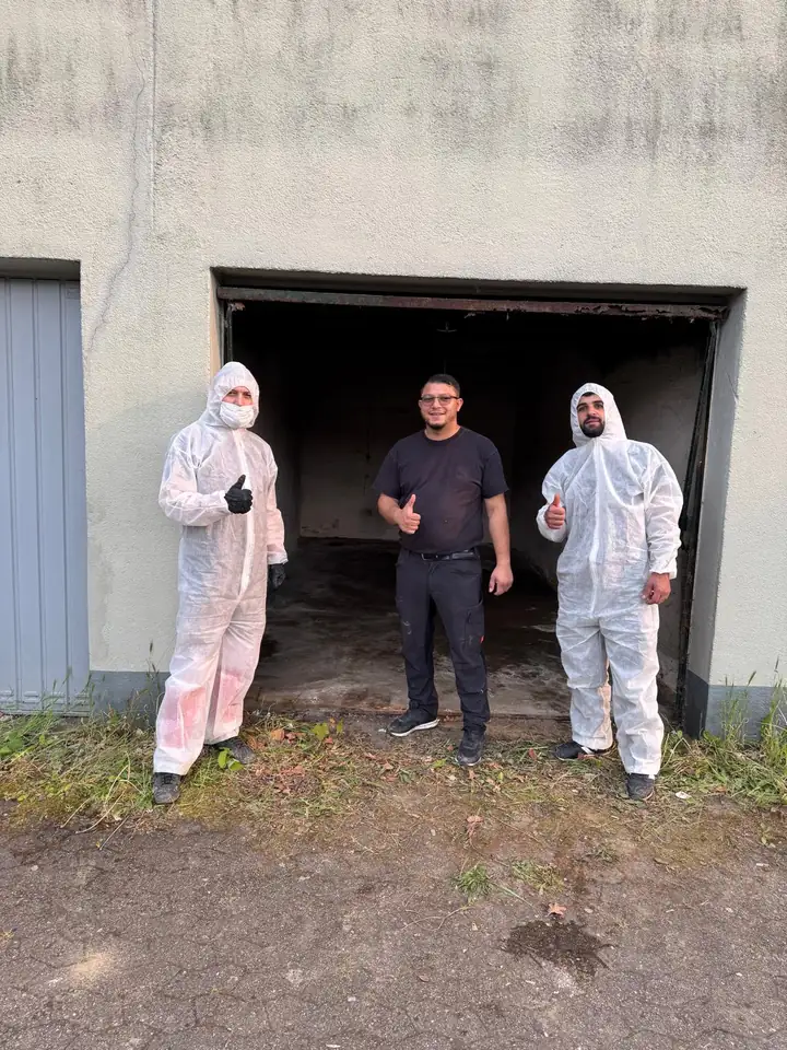 Drei Mitarbeiter vor der leer geräumten Garage